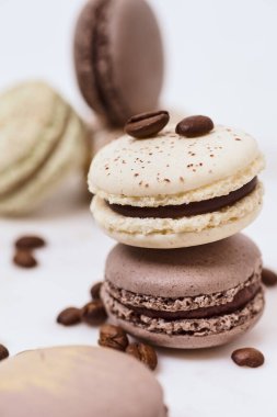 Beyaz arka planda birkaç renkli makaron ve kahve çekirdeği.