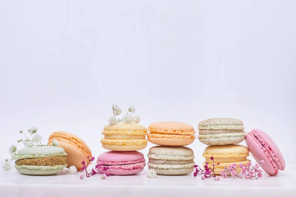 Beyaz arka planda birkaç renkli badem kurabiyesi ve çiçek.