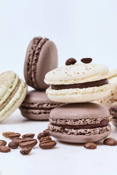 Beyaz arka planda birkaç renkli makaron ve kahve çekirdeği.