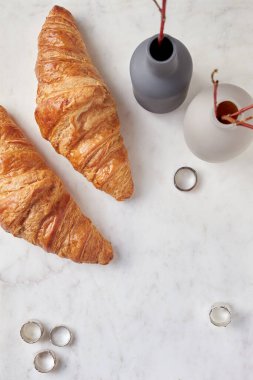 Beyaz mermer tahtada kruvasanlar, vazolar ve yüzükler. Düz Yatay
