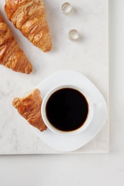 Kruvasan ve beyaz mermer tahtada bir fincan kahve. Düz Yatay