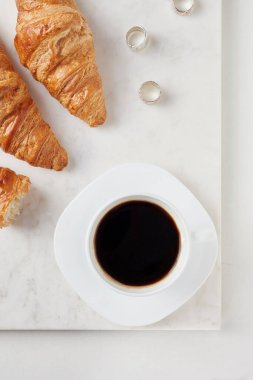 Kruvasan ve beyaz mermer tahtada bir fincan kahve.