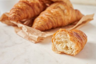 Parşömen kağıdındaki kruvasan. Marbel tahtasında.