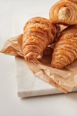 Parşömen kağıdındaki kruvasan. Marbel tahtasında.