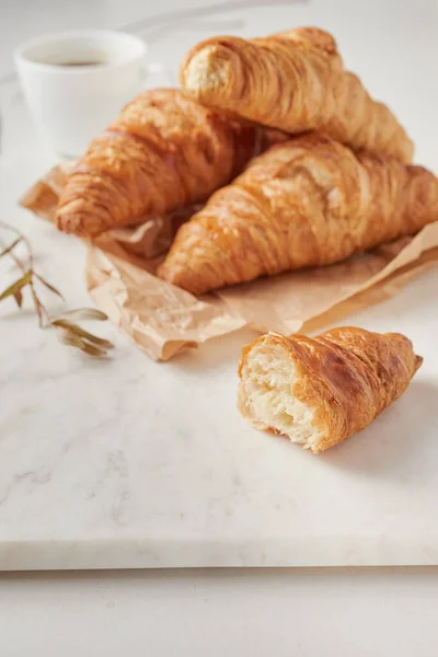 Croissants en el papel pergamino, en el tablero de marbel — Foto de Stock