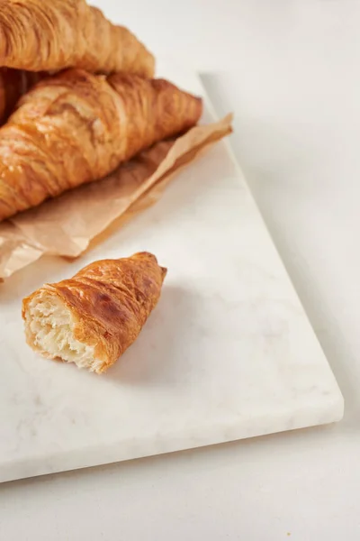 Croissants en el papel pergamino, en el tablero de marbel — Foto de Stock