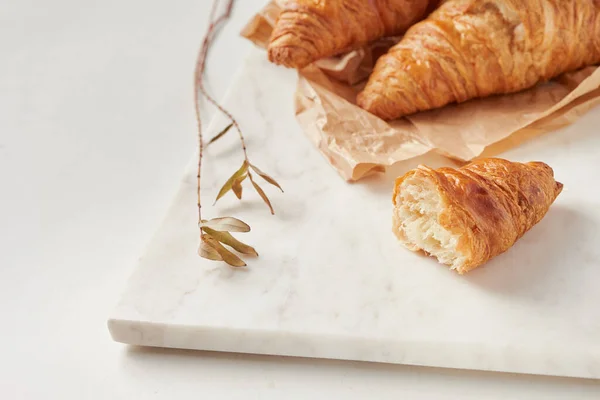 Croissants en el papel pergamino, en el tablero de marbel — Foto de Stock