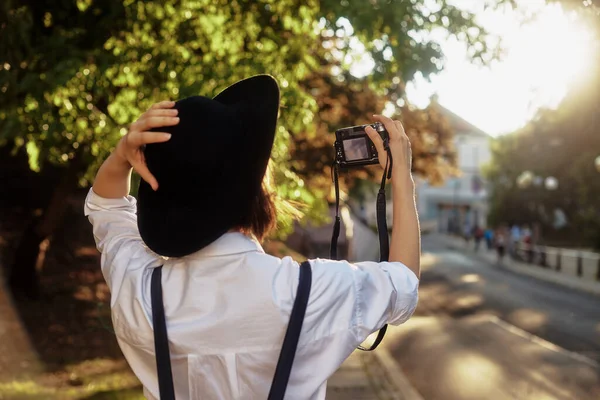 Dziewczyna w czarnym kapeluszu strzelająca w starym europejskim miasteczku. — Zdjęcie stockowe