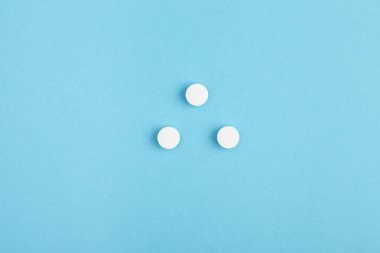 Mavi arka planda beyaz hapların yakın çekimi. İlaç yığını - tıbbi geçmiş
