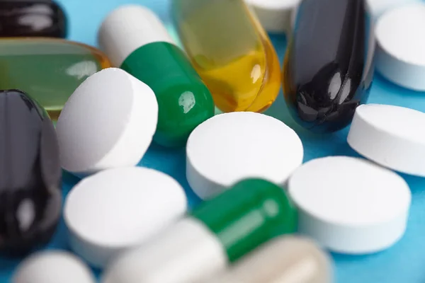 Beyaz pil ve renkli kapsüllerin yakınlaştırılması. İlaç yığını - tıbbi geçmiş