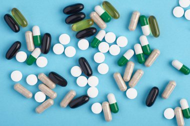 Beyaz pil ve renkli kapsüllerin yakınlaştırılması. İlaç yığını - tıbbi geçmiş