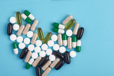 Beyaz pil ve renkli kapsüllerin yakınlaştırılması. İlaç yığını - tıbbi geçmiş