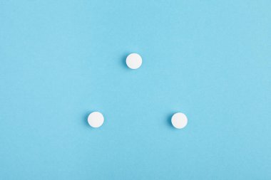 Mavi arka planda beyaz hapların yakın çekimi. İlaç yığını - tıbbi geçmiş