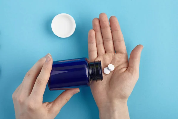 Beyaz haplar paketten bir elin üzerine dökülüyor. İlaç yığını - tıbbi geçmiş