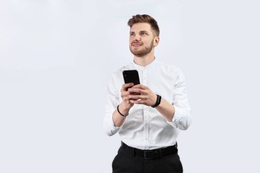 Beyaz gömlekli bir adam akıllı telefon kullanıyor ve heyecanlı. İzole et