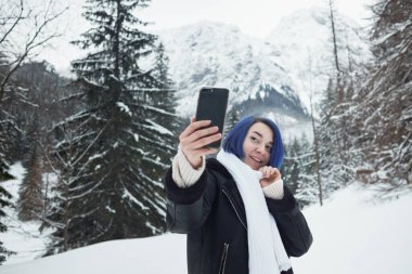 Dişi, dağ manzarasının arka planında resim çekiyor. Kış