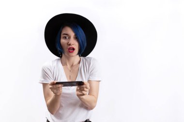 Beyaz tişörtlü bir kadın şaşırtıcı bir şekilde akıllı telefona bakıyor. Özetlenmiş