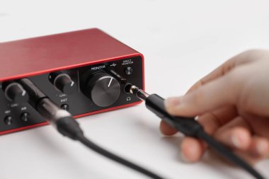 Kablolu Kablolarla Modern Ses Arayüzü takılı ve ses düğmesinde bir el var. Yakın plan.