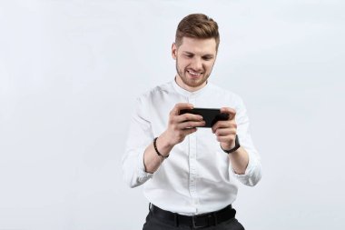 Beyaz gömlekli bir adam akıllı telefon kullanıyor ve heyecanlı. İzole et