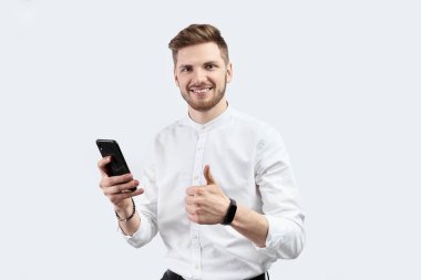 Beyaz gömlekli bir adam akıllı telefon kullanıyor ve heyecanlı. İzole et