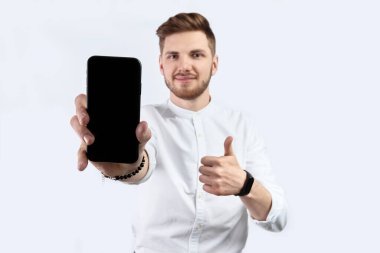 Beyaz tişörtlü bir adam akıllı telefondan kendini gösteriyor. İzole et