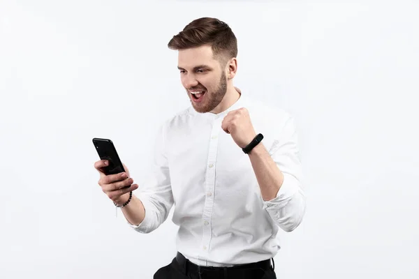 Beyaz gömlekli bir adam akıllı telefon kullanıyor ve heyecanlı. İzole et