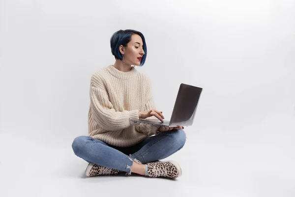 Yerde oturan ve elinde dizüstü bilgisayarı olan bir kadın. İzole edilmiş