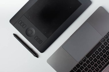 Beyaz arkaplanda siyah grafik tasarım tableti, stil ve dizüstü bilgisayarın en üstteki görüntüsü.