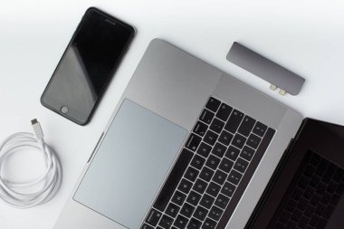 Üst görüntü fotoğrafı, siyah akıllı telefon, USB tip-c kablo, USB merkez ve beyaz arkaplanda bir laptop..