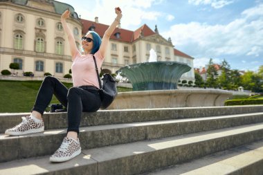 Avrupa bahçesinde merdivenlerde oturan genç bir bayan gezgin. Yaz seyahati