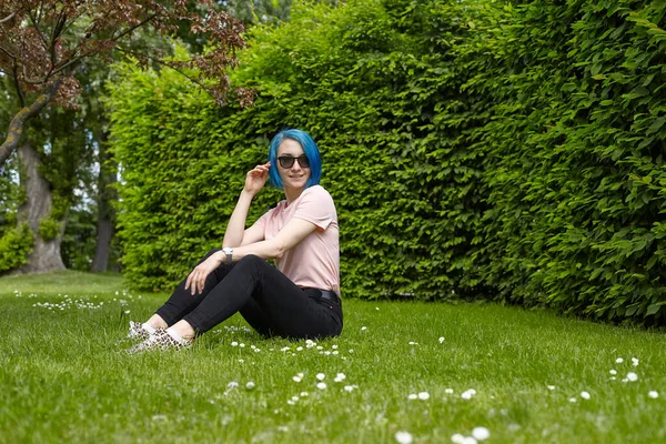 Genç bir gezgin bir Avrupa bahçesindeki çimlerin üzerinde oturuyor. Yaz seyahati