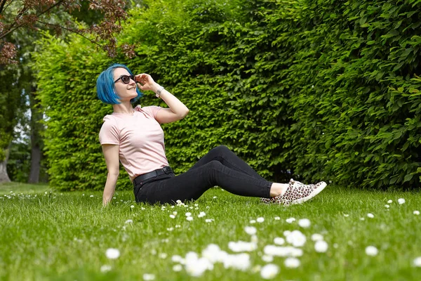 Genç bir gezgin bir Avrupa bahçesindeki çimlerin üzerinde oturuyor. Yaz seyahati