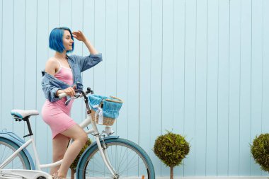 Mavi duvarında kova olan beyaz bisikletli tatlı bir kız. Yaz mevsiminde güney yakasında.