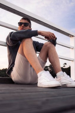 Aktif ve sağlıklı genç erkekler iskelede gün batımının keyfini çıkarıyorlar. Yaz tatili