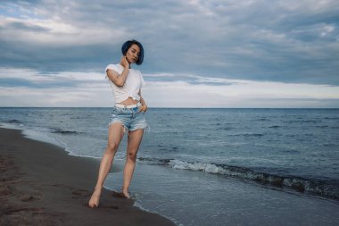 Aktif ve sağlıklı genç bir kadın, kumlu bir baltık plajında eğleniyor. Yaz tatili