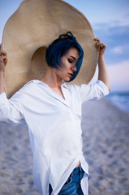 Kumlu Baltık sahilinin tadını çıkaran şapkalı aktif, sağlıklı genç bir kadın. Yaz tatili