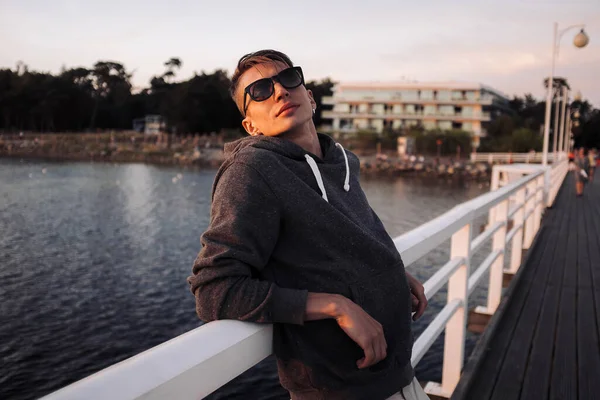 Aktif ve sağlıklı genç erkekler iskelede gün batımının keyfini çıkarıyorlar. Yaz tatili