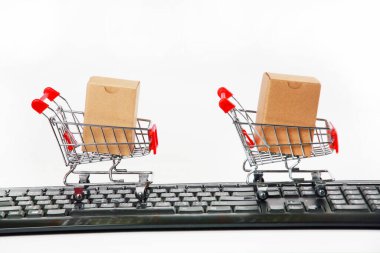 Bilgisayar klavyesinde kutuları olan alışveriş arabaları beyaz arka plan 