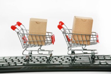 Bilgisayar klavyesinde kutuları olan alışveriş arabaları beyaz arka plan 