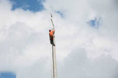 Mavi gökyüzü arka planına sahip elektrik direğinde inşaat işçisi.