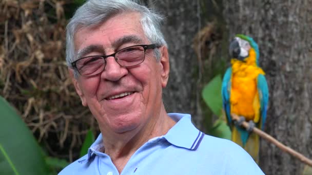 Hombre mayor sonriendo con loro — Vídeo de stock