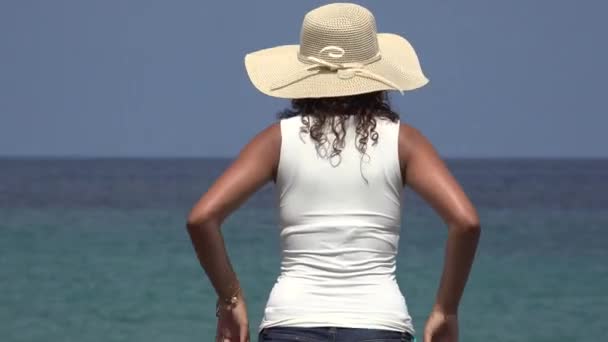 Mujer usando sombrero mirando fijamente al océano — Vídeos de Stock