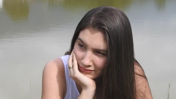 Teen girl daydreaming und sitzen am see — Stockvideo