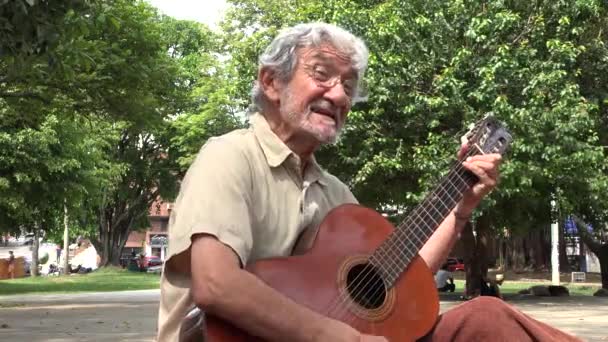 Человек играет на акустической гитаре и поет — стоковое видео