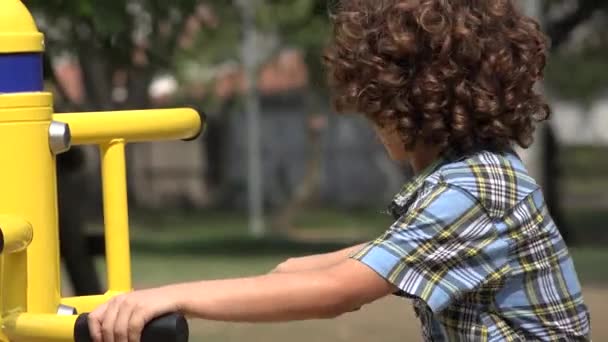 Kręcone włosy chłopak o plac zabaw dla dzieci — Wideo stockowe