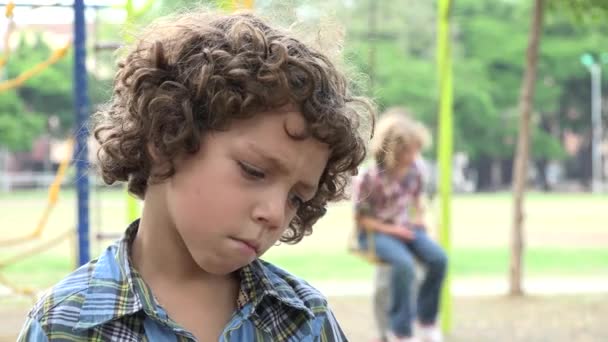 Rapaz triste no parque infantil — Vídeo de Stock