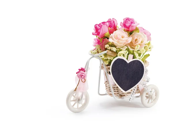 Rose flowers in bicycle basket with heart clothes pin on white b — Stock Photo, Image