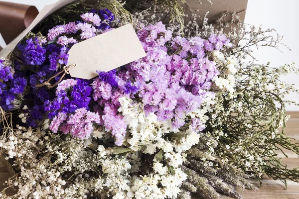 Ramo de flores secas con etiqueta de papel en blanco en la mesa de madera —  Fotos de Stock