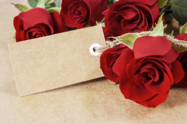Red roses with blank paper tag on brown paper clipart