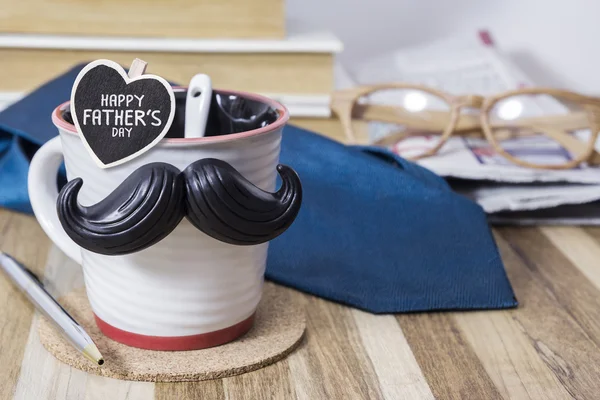 Cup with mustache on wooden table for fathers day concept
